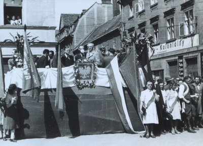 Czarnobiała fotografia przedstawiająca mężczyzn i kobiety idących w pochodzie ulicami miasta.