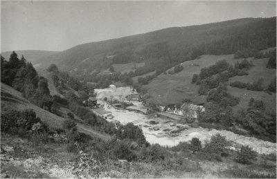 Czarnobiałe zdjęcie budowy tamy nad rzeką.