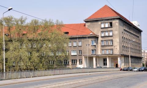 Trzypiętrowy, duży, szary stary budynek o prostych kształtach pokryty pomarańczową dachówką będący obecną siedzibą Archiwum Państwowego we Wrocławiu