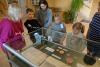 Trzy kobiety w średnim wieku i troje małych dzieci w wieku ok. 8-10 lat stoją w holu archiwum przy szklanej gablocie wystawowej z kopiami starych dokumentów sygnowanych pieczęciami. Przyglądają się z zainteresowaniem.