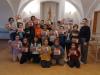 Grupa dzieci ze szkoły podstawowej wraz z opiekunami pozują do fotografii grupowej trzymając w dłoniach swoje prace ręczne.