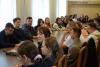 Sala konferencyjna, przy długim stole siedzi liczna grupa studentów. Jedna studentka mówi do mikrofonu, pozostali słuchają.